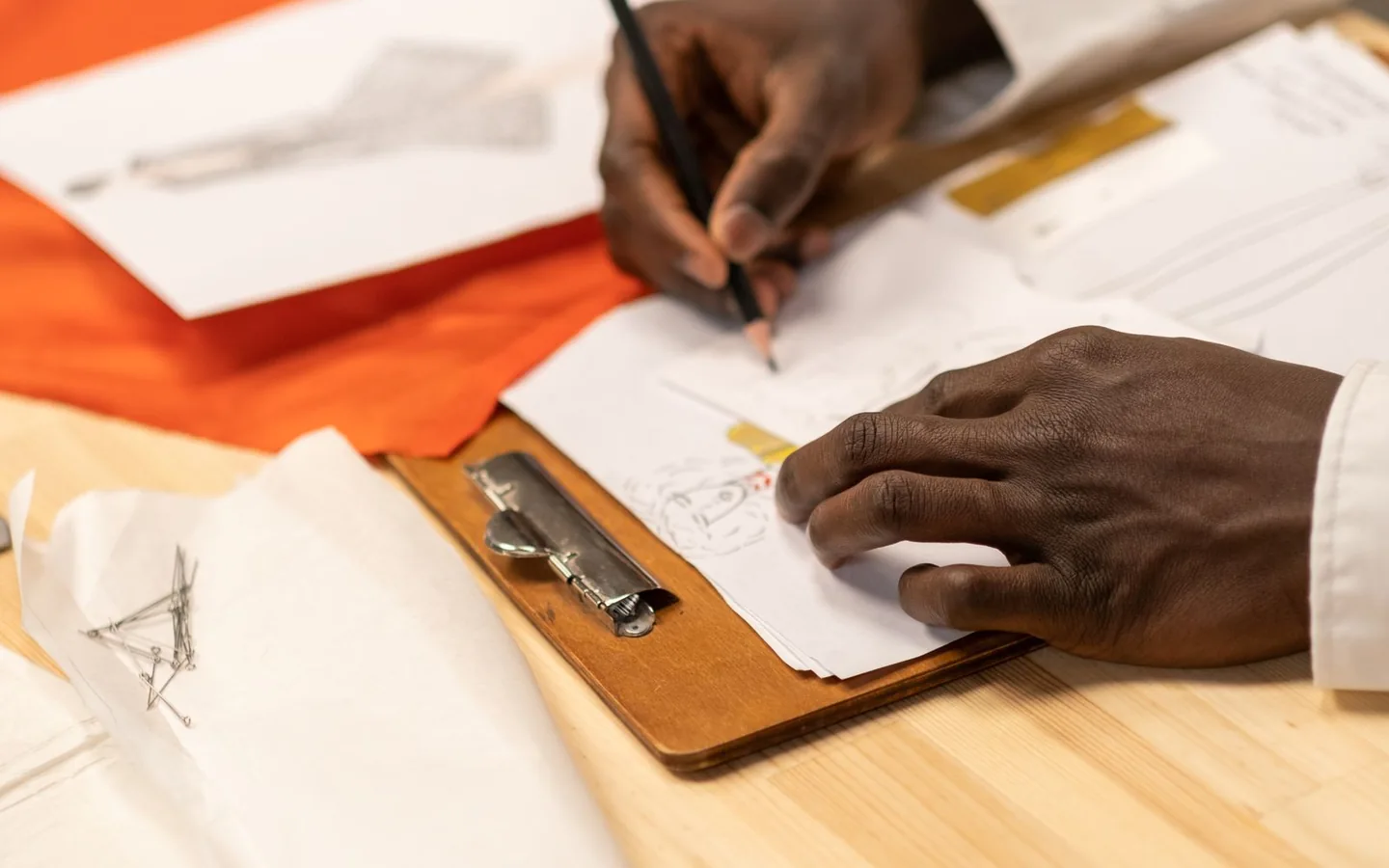 Close-up of hands developing fashion sketches on a desk