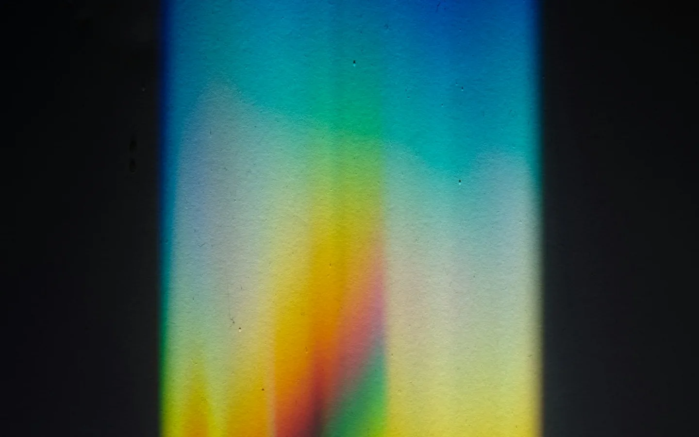 A spectrum of coloured light on a dark surface