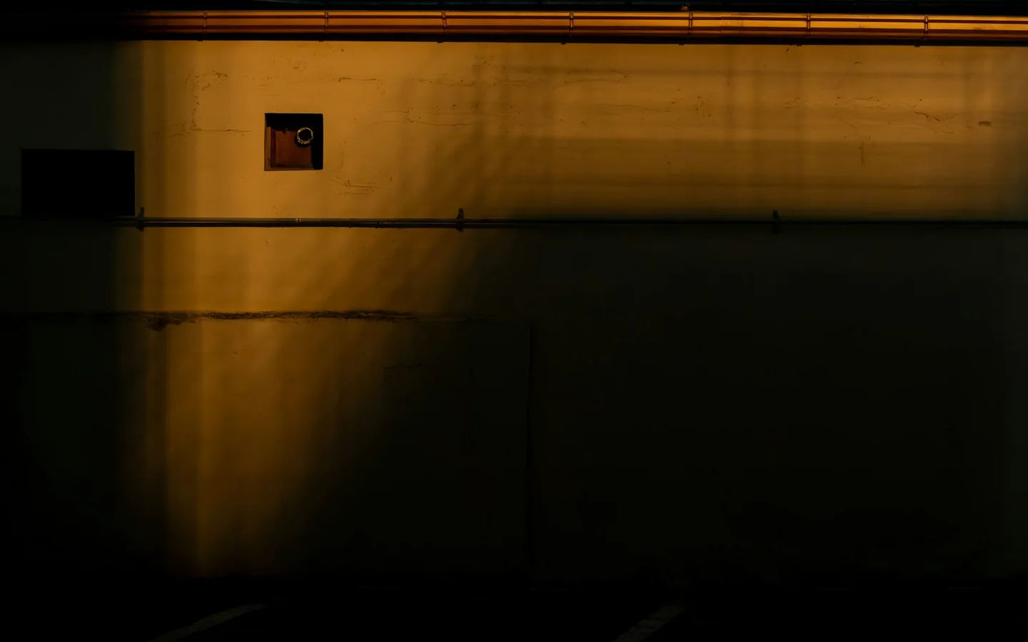 A warm-lit concrete wall and a small geometric window
