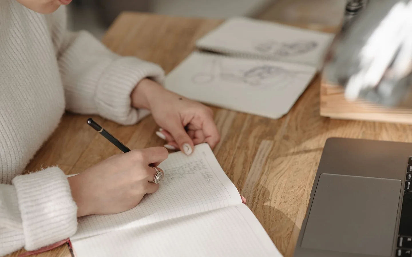 Written notes and sketches developed beside a laptop on a wooden desk